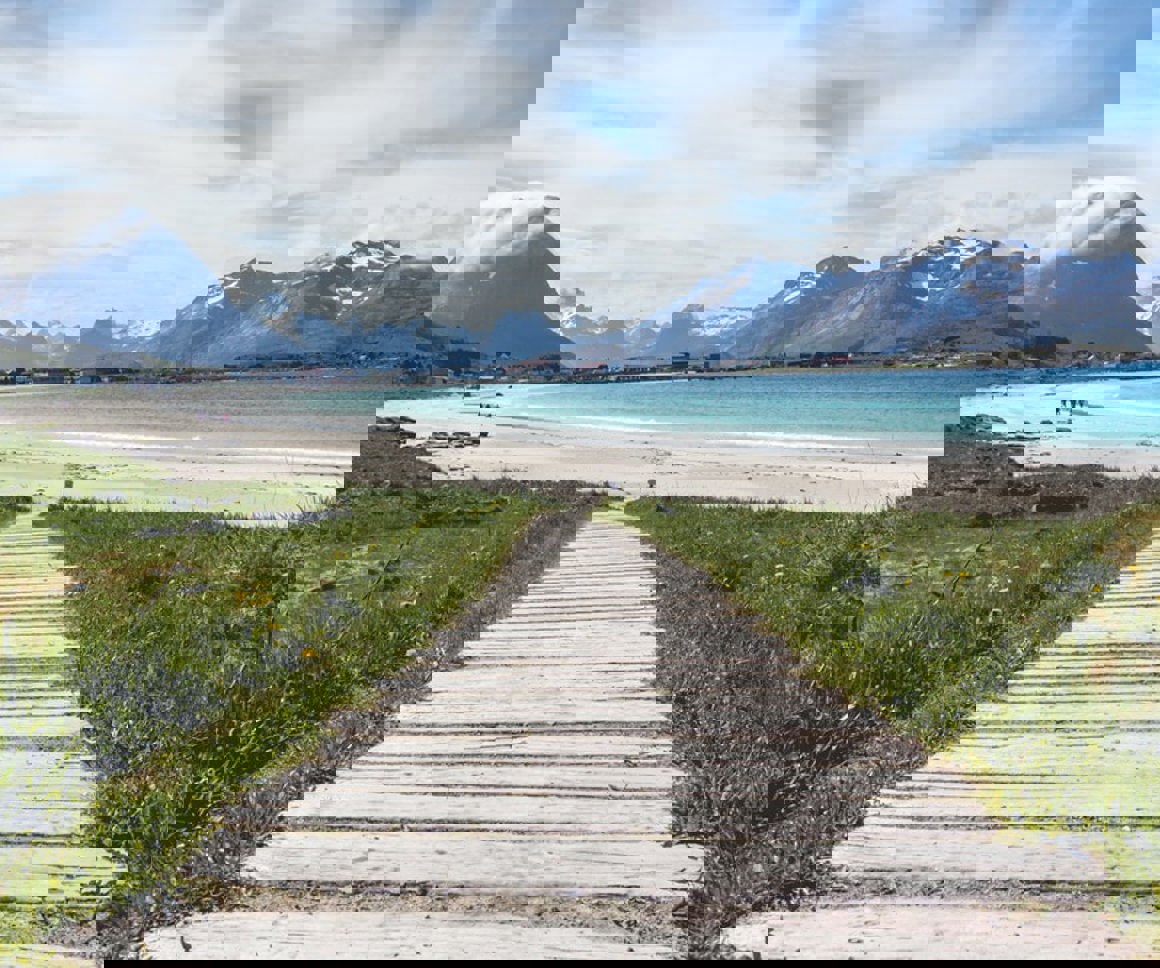 Path going down to a beach with mountains in the distance