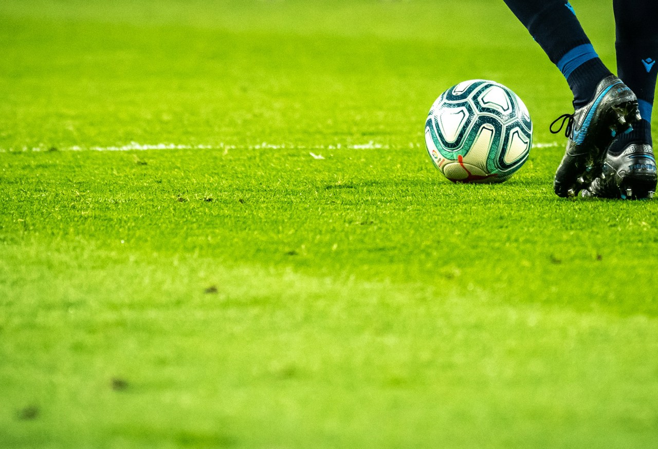 Footballer on a grassy pitch approaching a football