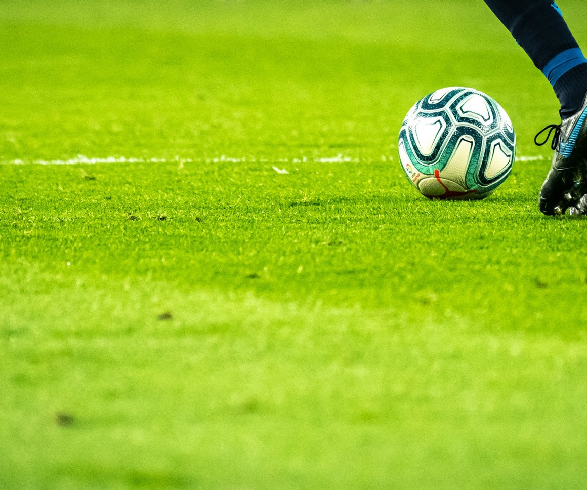 Footballer on a grassy pitch approaching a football