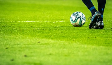 Footballer on a grassy pitch approaching a football