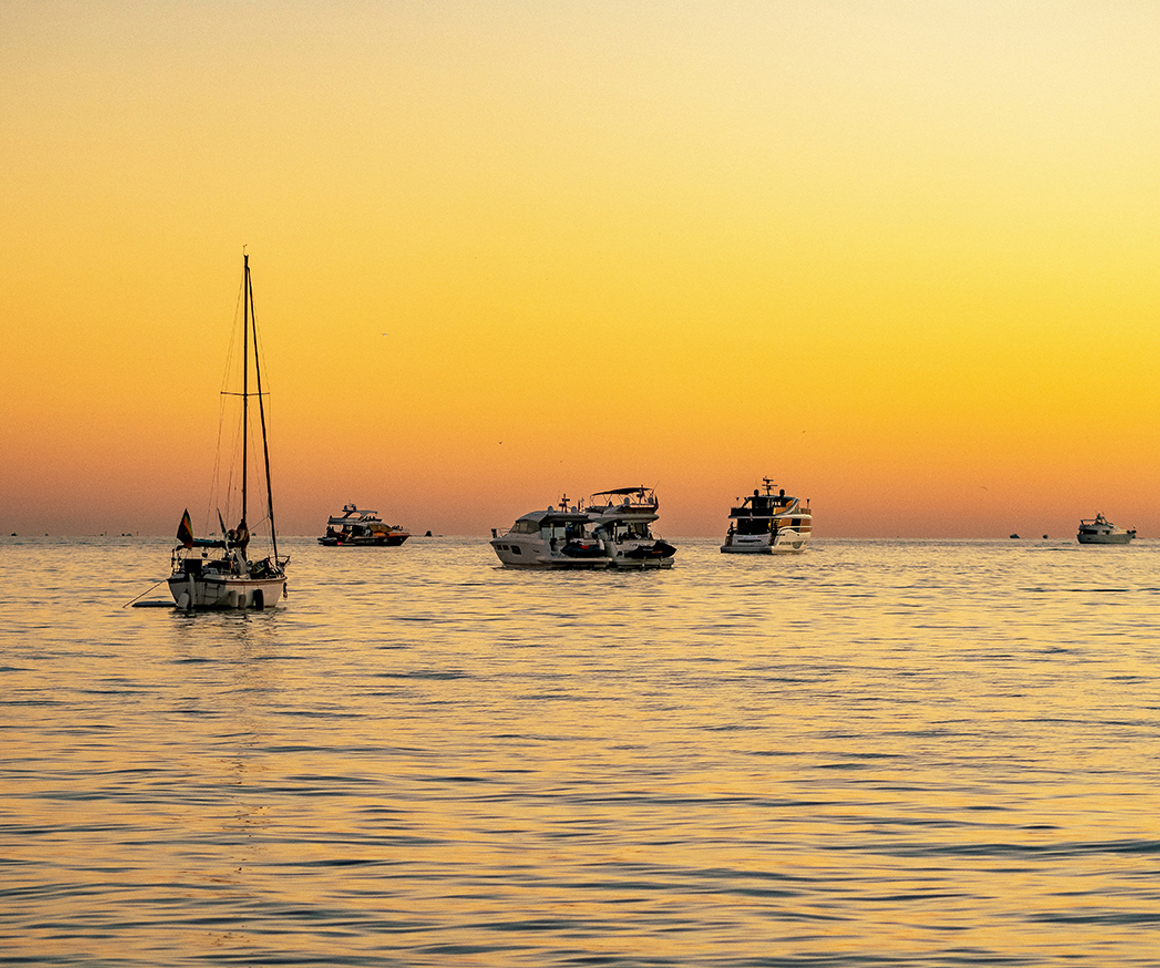 Yachts on water against a yellow sky
