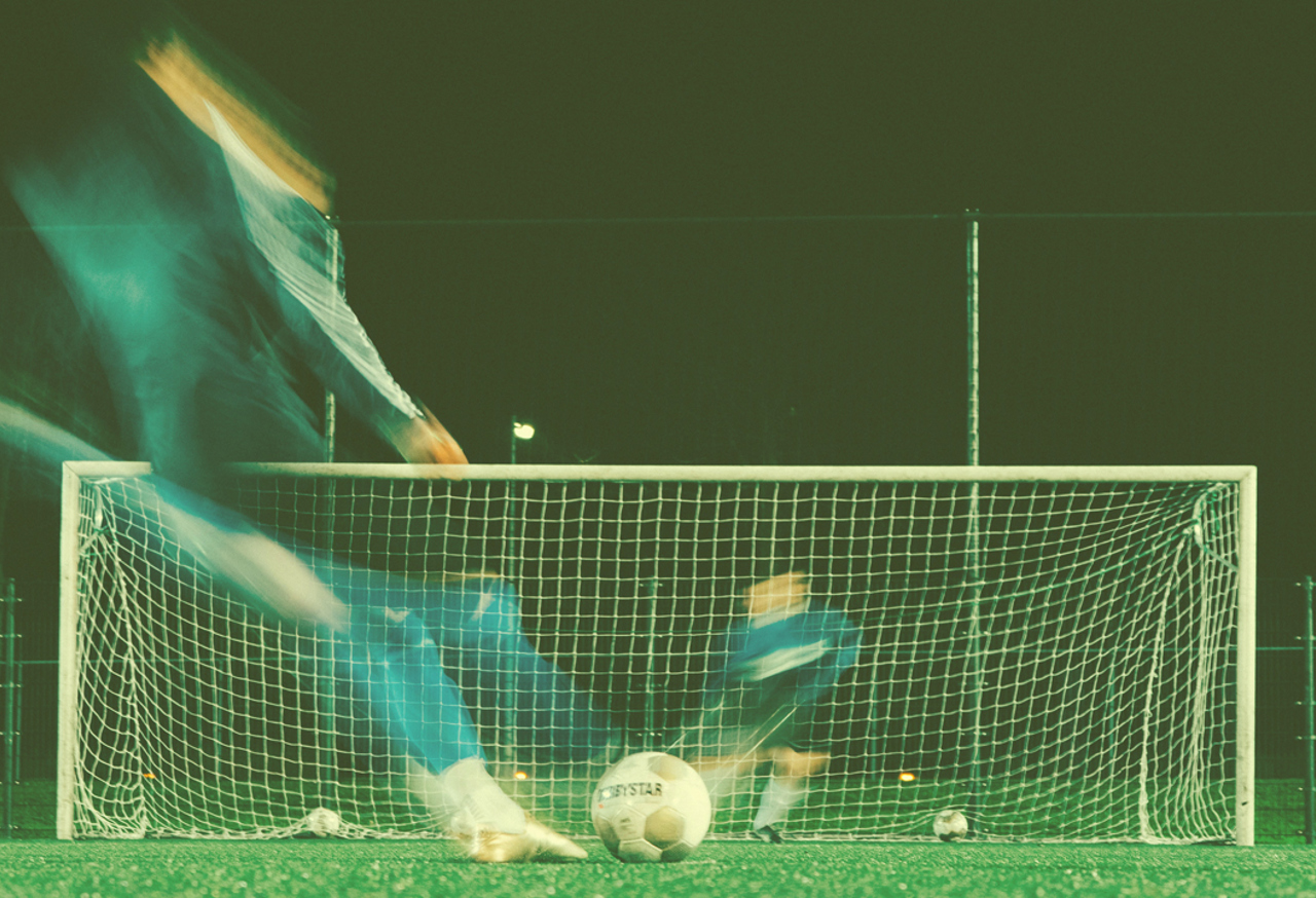 Footballer kicking a ball into a goal