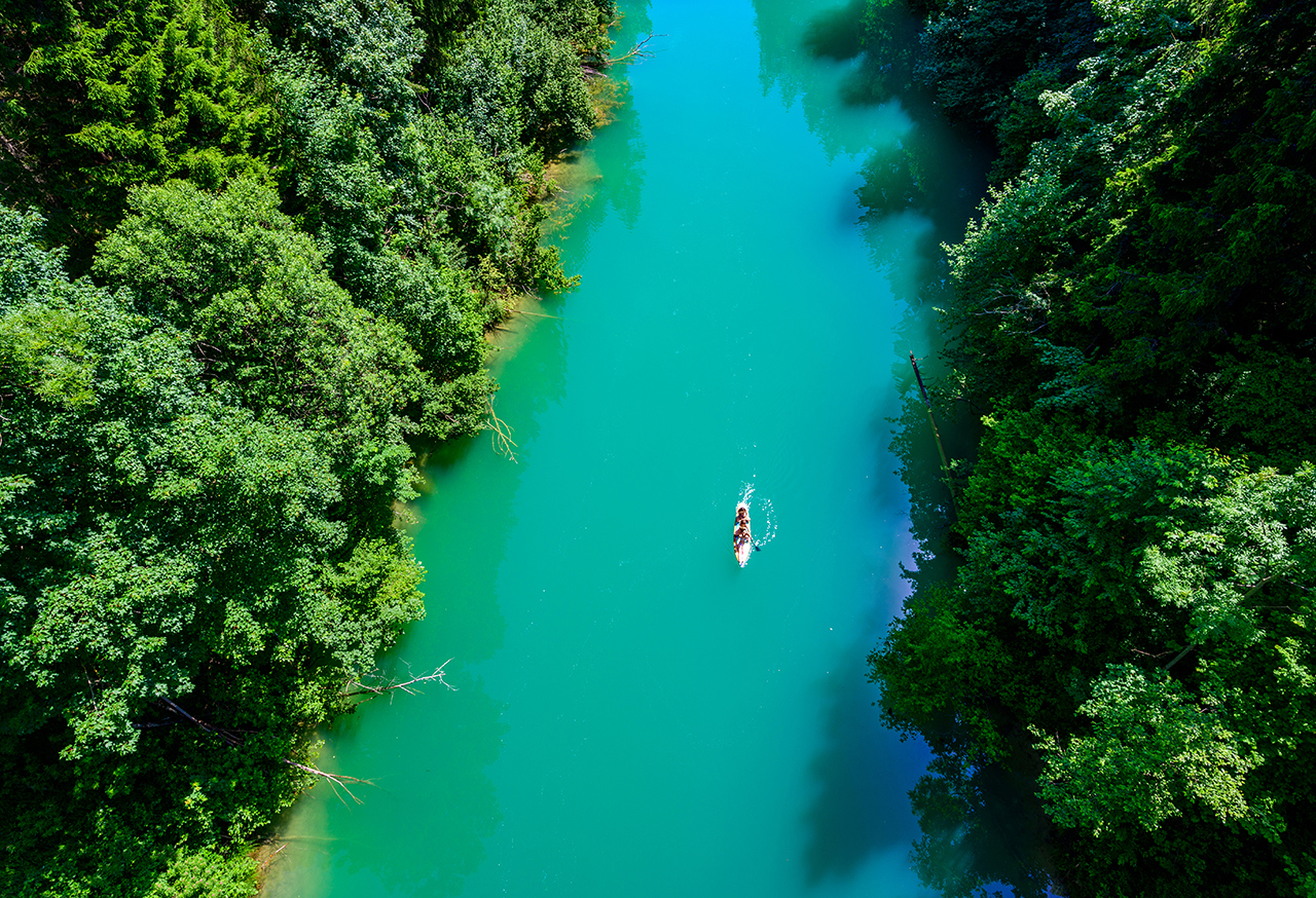 Canoeist travelling on a river with forest each side