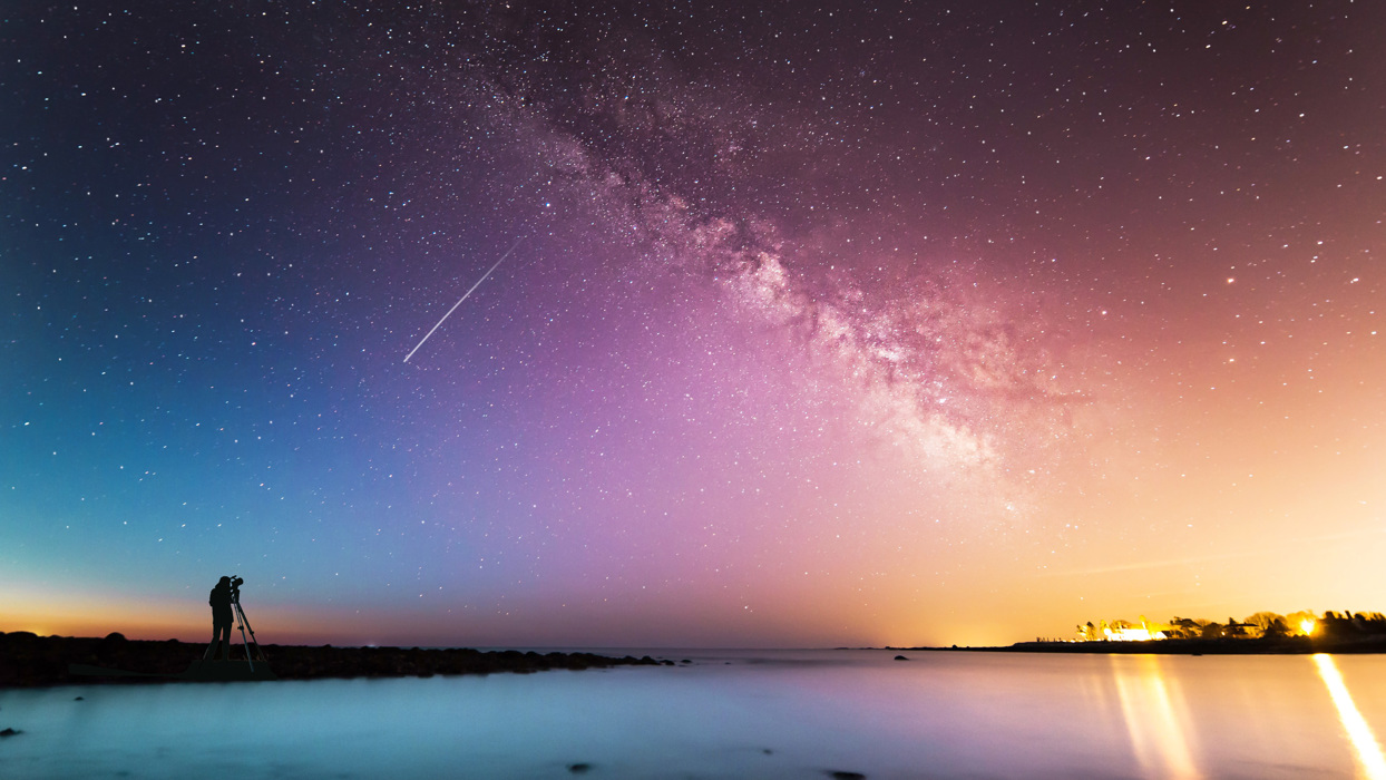 Person looking through telescope at galaxy