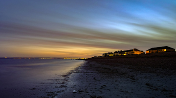 Houses looking out over a beach at sunset