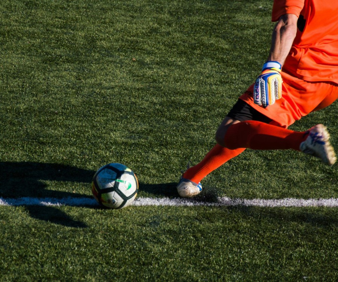 Football in red kit kicking a football