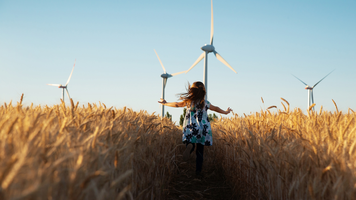 Child Running In A Corn Field Towards A Wind Turbine