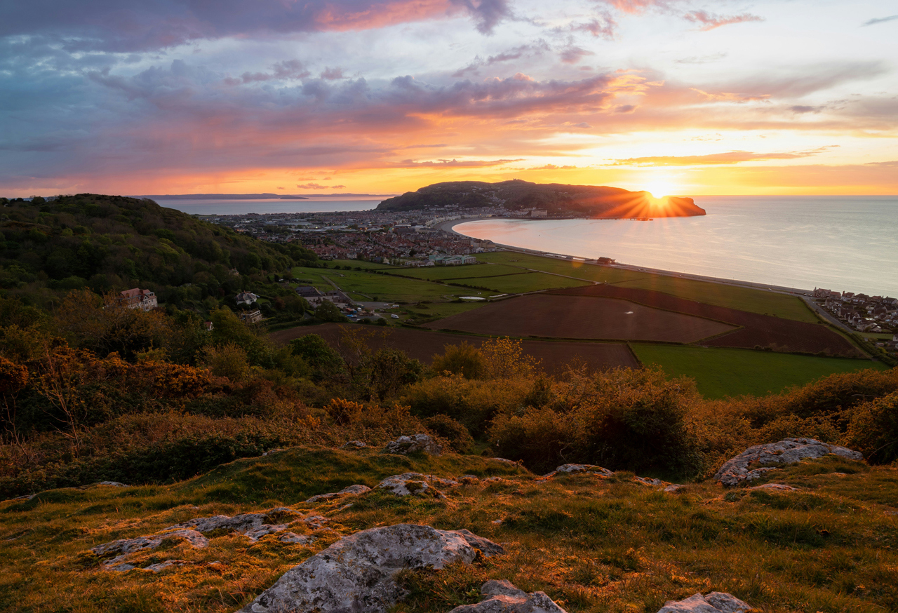 View of seaside town over fields at sunset