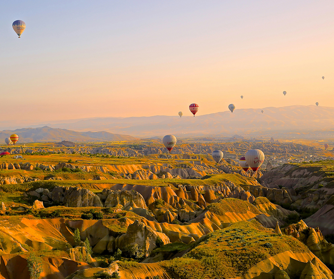 Hot air balloons flying over rocky desert landscape