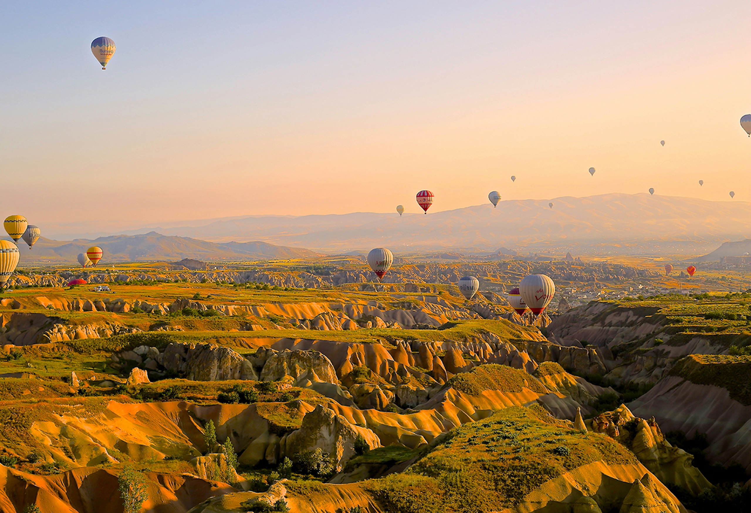 Hot air balloons flying over rocky desert landscape