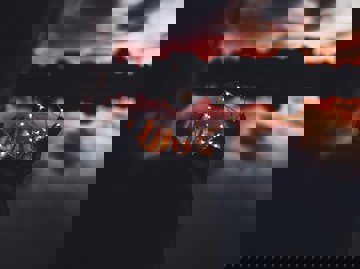 Person Holding Fairy Lights Against An Atmospheric Sky