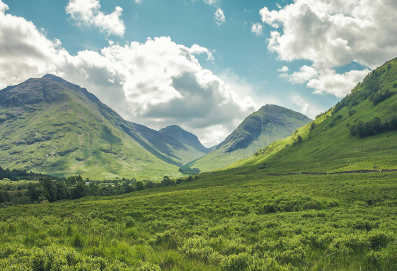 A green valley with clouds in the sky