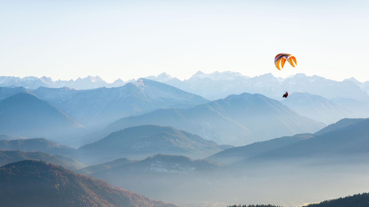 Person Gliding Against A Mountain Backdrop